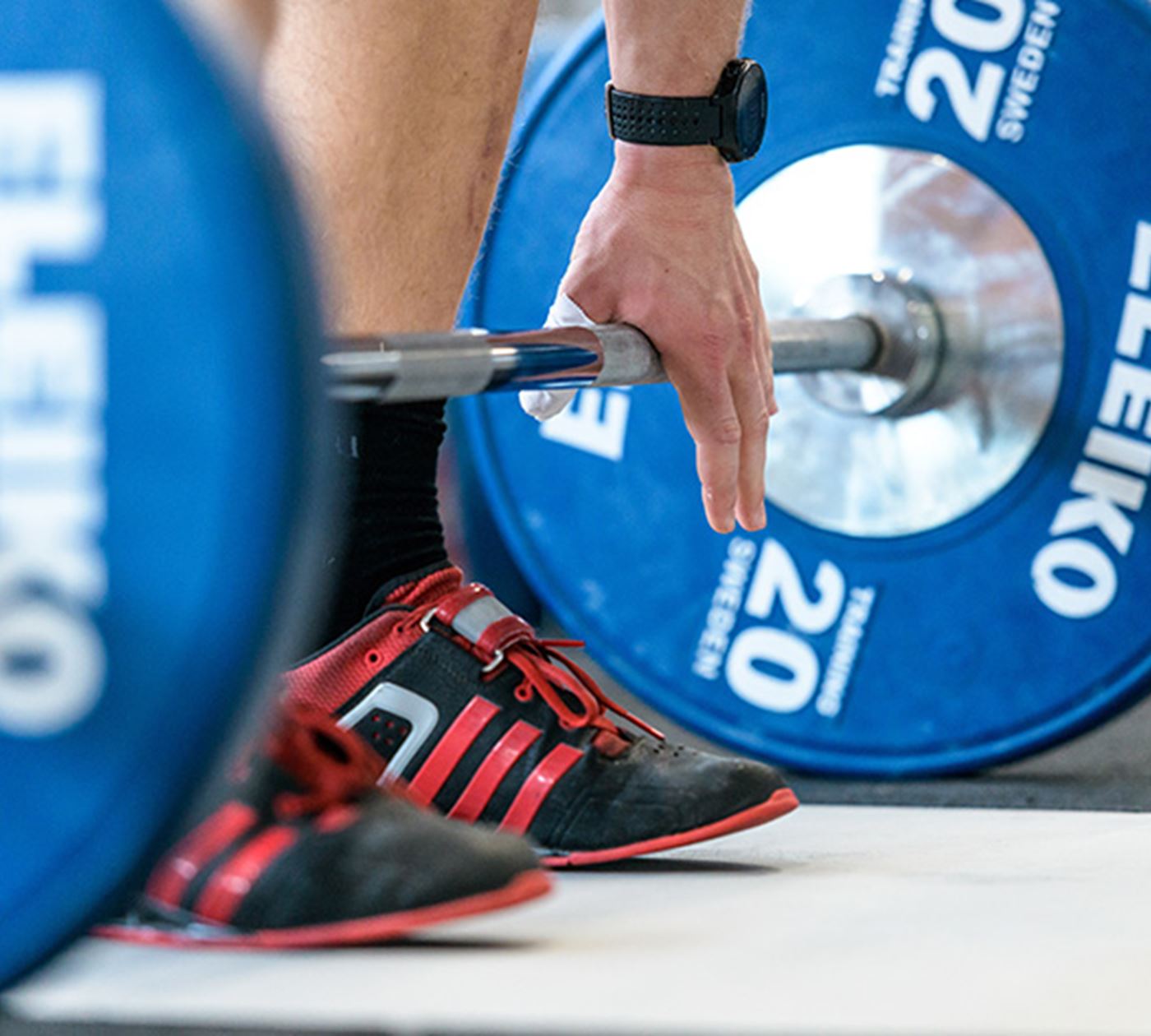A person standing over a barbell with blue weights on it