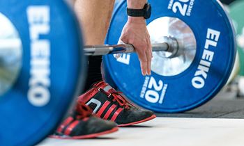 A person standing over a barbell with blue weights on it