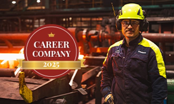 A steel worker standing in a production site posing with a logo next to him.